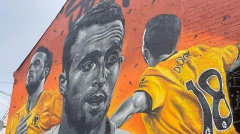 A mural depicting Diogo Jota in black and white in the middle and the player also wearing Wolves' strip to the left and right.