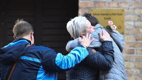 Mourners hug in front of the synagogue in Halle, 10 October