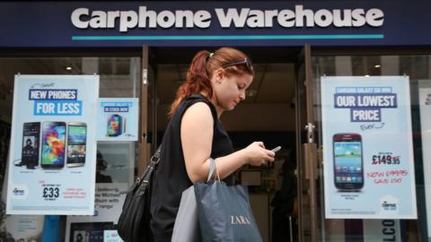 Woman walks past Carphone Warehouse store