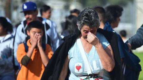 A parent and student are seen holding their faces while reacting to shooting at LA school