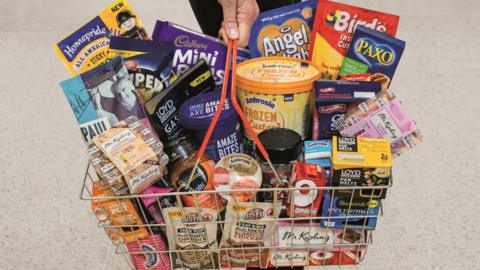 A shopper carries a basket of Premier Food products