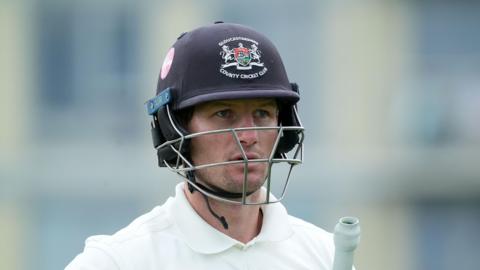 Cameron Bancroft with his navy blue Gloucesteshire helmet on and his bat under his left arm