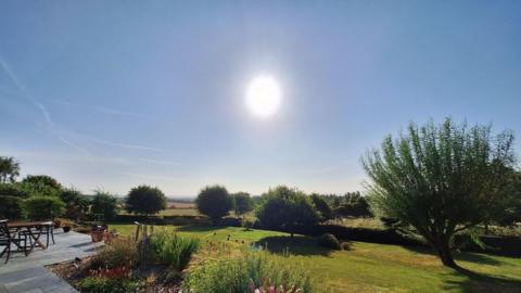 Sunny landscaped garden with flowers, lawn and countryside views in Bowden, The Scottish Borders