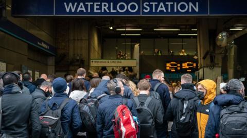 Commuters queue for the underground to resume at Waterloo station in London, as tube services remain disrupted following a strike