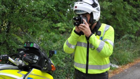 A police officer using a hand-held speed camera