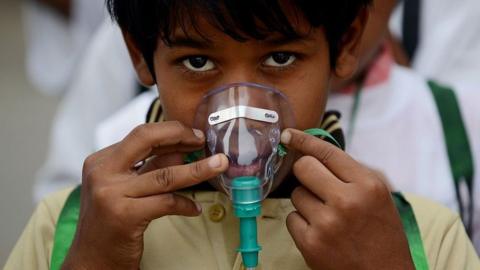 An Indian schoolchild adjusts his facemask before the start of an event to spread awareness of the problem of air pollution in New Delhi on June 4, 2015, on the eve of World Environment Day.