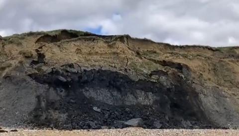 Still from video off cliff collapse. A large chunk off earth can be seen sliding down the cliff.