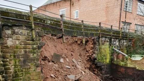 A photograph shows earth and rubble slipping from the side of Chester's Roman wall.