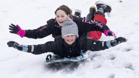 Two girls on a sled on a golf course near Penicuik, Midlothian