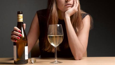 Young woman with wine bottle and full glass