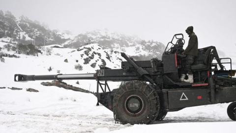 Picture taken on April 3, 2023 shows an Indian army soldier on a Bofors gun at a camp near Pankang Teng Tso Lake in the Tawang district of India's Arunachal Pradesh state. - Freshly laid roads, bridges, upgraded military camps, and new civilian infrastructure dot the winding high Himalayan route to the Indian frontier village of Zemithang -- which China renamed last month to press its claim to the area. It is in the far northeastern Indian state of Arunachal Pradesh, almost all of which Beijing insists falls under its sovereignty as "South Tibet"