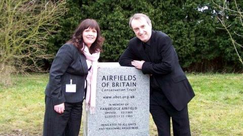 ABCT trustee Lynda Coxon with ABCT director-general Kenneth Bannerman standing at a memorial