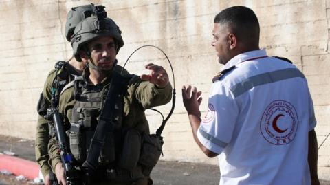 Israeli soldier and Palestinian medic gesture to one another at scene of shooting (25/07/23)