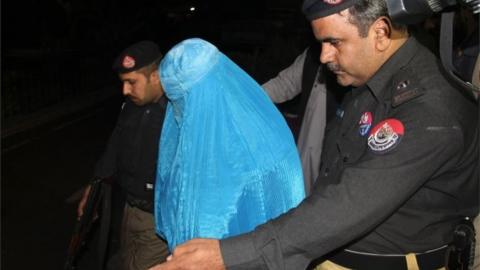 Pakistani policemen escort Afghan refugee woman Sharbat Gula (C) as she leaves the Lady Reading Hospital where she was treated, in Peshawar on November 9, 2016, before her deportation to Afghanistan.