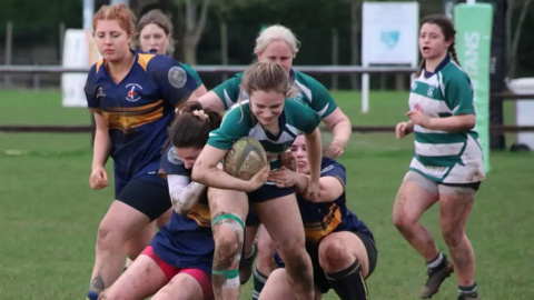 A picture of Reading Rugby Club women players playing against another team. A woman is running with the ball towards the camera. 