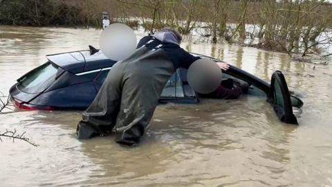 A stranded driver is helped from his car.