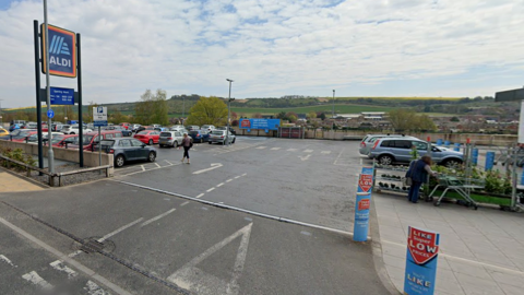 A wide shot of the entrance to the Aldi car park in Salisbury with countryside in the background