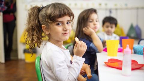 Preschool students sitting in classroom having lunch.