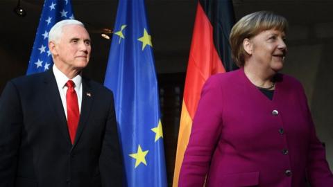 German Chancellor Angela Merkel (R) and US Vice President Mike Pence (L) leave after a photo call during the 55th Munich Security Conference