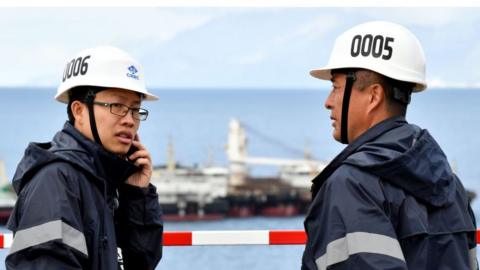 A Chinese worker and engineer speaks on the phone next to one of his colleague, on April 11, 2019, in Peljesac