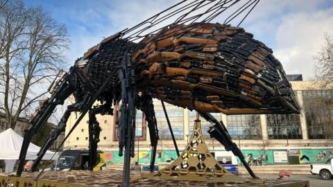 A giant bee sculpture made out of knifes and guns