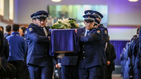 New Zealand police officers carry Constable Matthew Hunt's coffin out of his funeral service