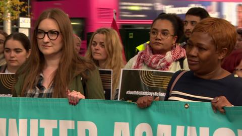 Two women hold an anti racism banner