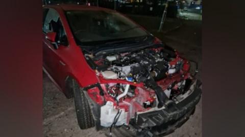 A red car which has been stripped