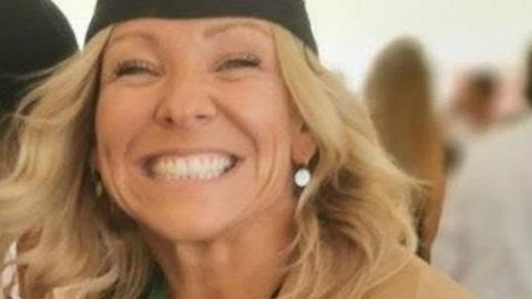 A happy smiling woman wearing a university cap.