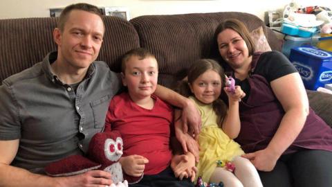 Nate (second left) with his family sitting on a sofa