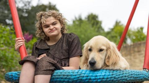 Josselin sitting on a seat with her guide dog Stormzy