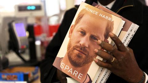 Professor Chris Imafidon holds three copies of the book "Spare", by Britain's Prince Harry, Duke of Sussex during a special midnight opening event for the release of the memoire, at the WHSmith bookstore, at Victoria Station in London, on January 9, 2023
