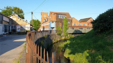 The Tower Building at St Michael's Trading Estate in Bridport and the River Brit in the foreground