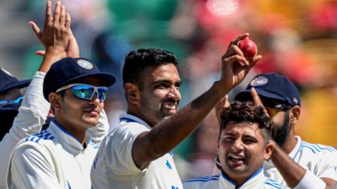 India spinner Ravichandran Ashwin holds up the ball after taking a five-wicket haul as his team-mates applaud him