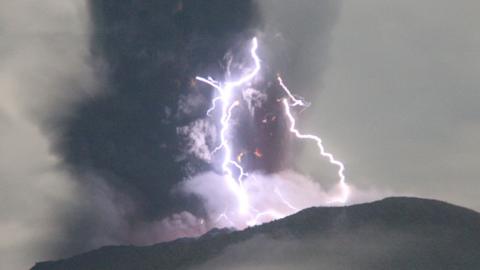 Large lightning strikes taking place on the top of an erupting volcano