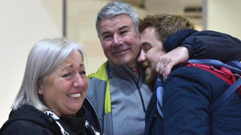 A mother cried as a father hugs his son after he arrives at Belfast City Airport