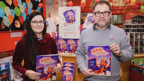 Karmen and Rob Cowley holding copies of the book