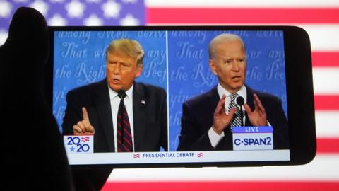 US President Donald Trump and Democratic presidential candidate and former US Vice President Joe Biden are seen during the first presidential debate on a YouTube video displayed on a screen of a smartphone.