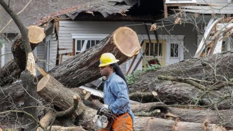 Terrance Miller with East Point Power helps clear a large tree which fell and hit a home and several cars as thunderstorms moved through East Point, Georgia, on 3 January 2017.