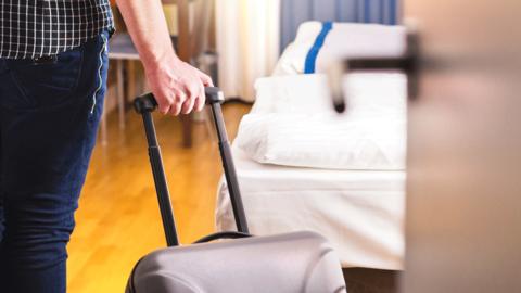 Man entering hotel room with case