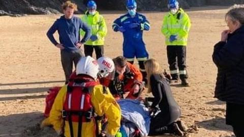 Woman being attended to on a stretcher on the beach