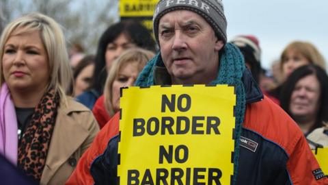 Protestor holding a "no border, no barrier" sign