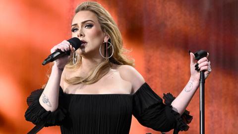 Adele performs on stage, she's wearing a black dress