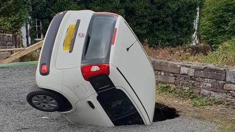 A white Fiat in a sinkhole