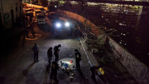 Police investigators inspect the body of John Estrella, 18, who was allegedly killed by unidentified assailants on 26 June 2017 in Manila, Philippines.