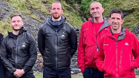 Tommy and Max next to two mountain rescuers