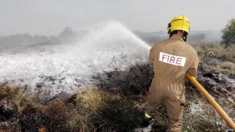 Firefighter uses hose on burning gorse