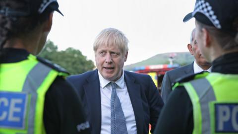 Boris Johnson standing with two police officers