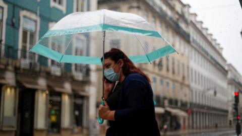 A woman wearing a mask walks in Lisbon
