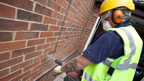 A man installing cavity wall insulation